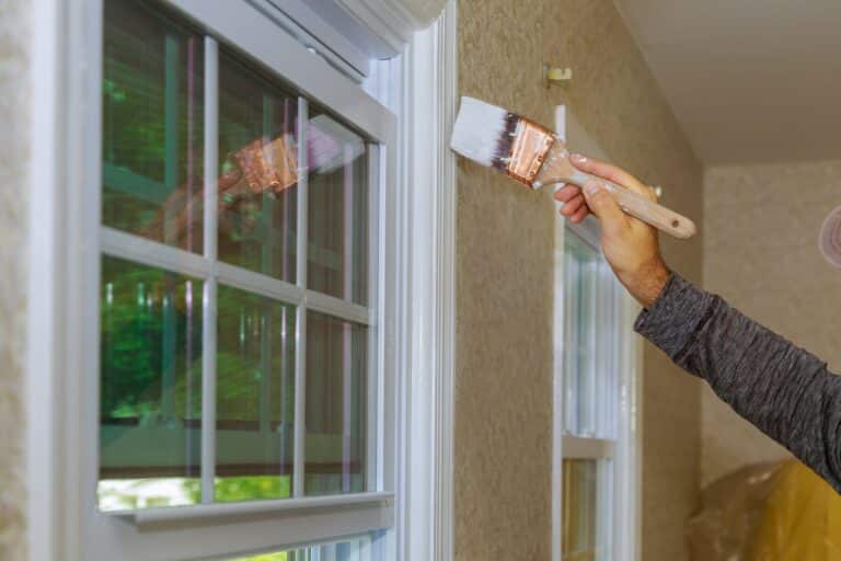 Painter painting a window trim or molding of a house